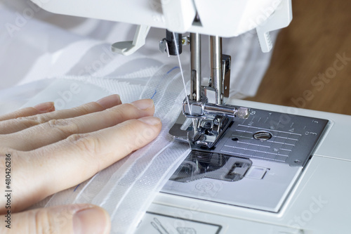 Hemming the edges of the curtains with curtain tape on a sewing machine.
