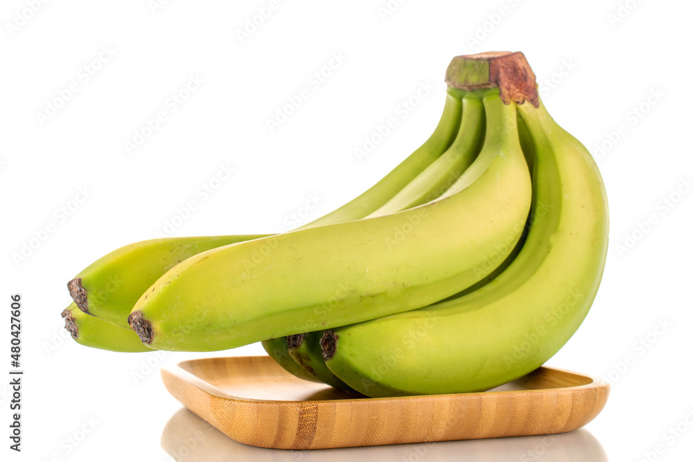 One bunch of organic green bananas on a bamboo plate, close-up, isolated on white.