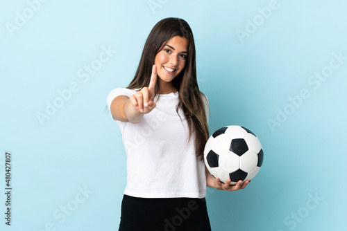 Young football player brazilian girl isolated on blue background showing and lifting a finger