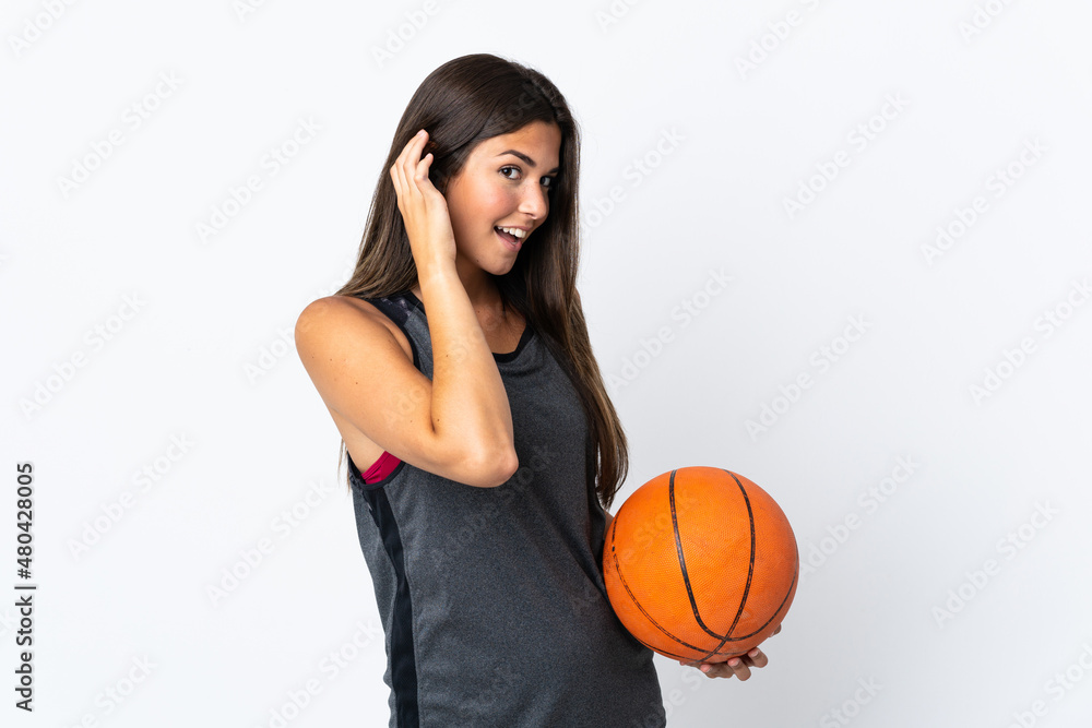 Young brazilian woman playing basketball isolated on white background listening to something by putting hand on the ear Young brazilian woman playing basketball isolated on white background listening to something by putting hand on the ear
