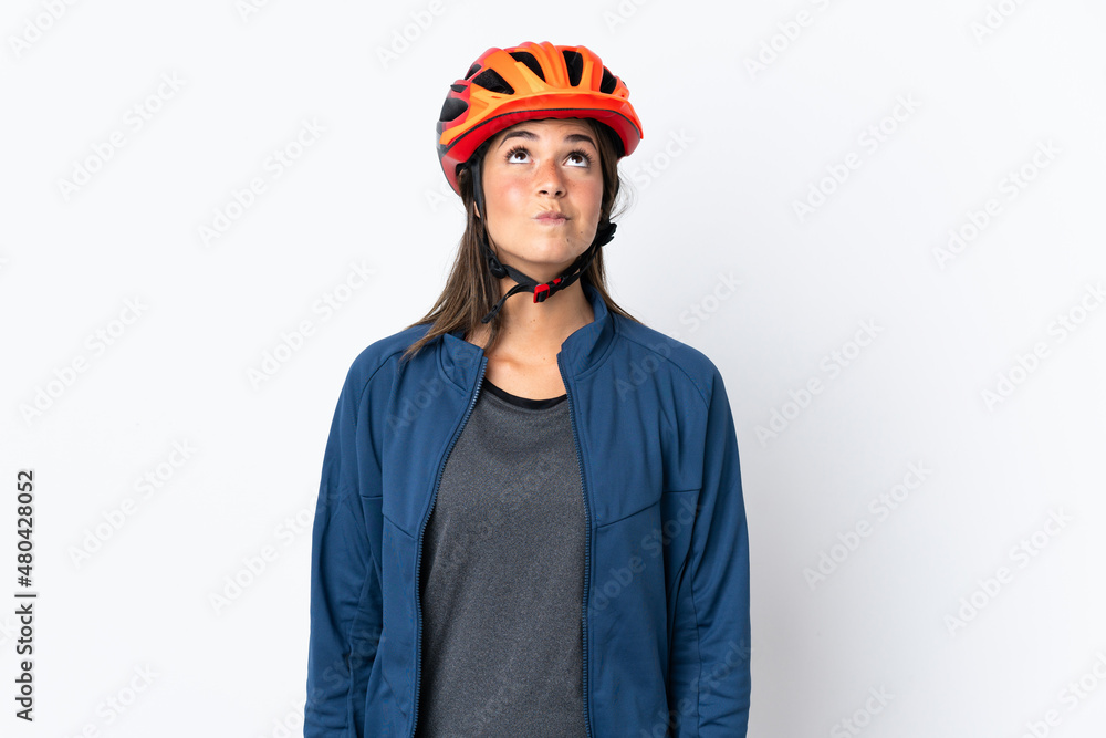 Young cyclist brazilian girl isolated on white  background and looking up - obrazy, fototapety, plakaty 
