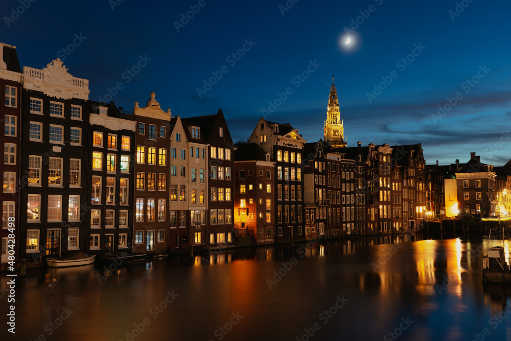 Old warehouses along the Damrak during sunset in the center of Amsterdam
