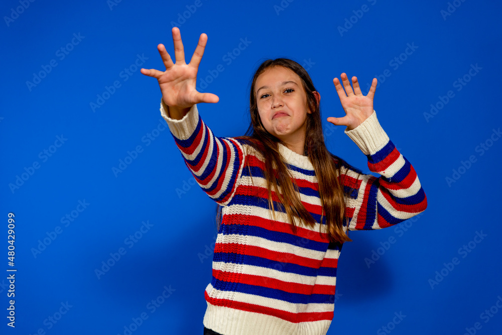 Photo of funny funky preteen girl hands claws roaring wearing a striped sweater isolated aquamarine background. Photo of funny funky preteen girl hands claws roaring wearing a striped sweater isolated aquamarine background.