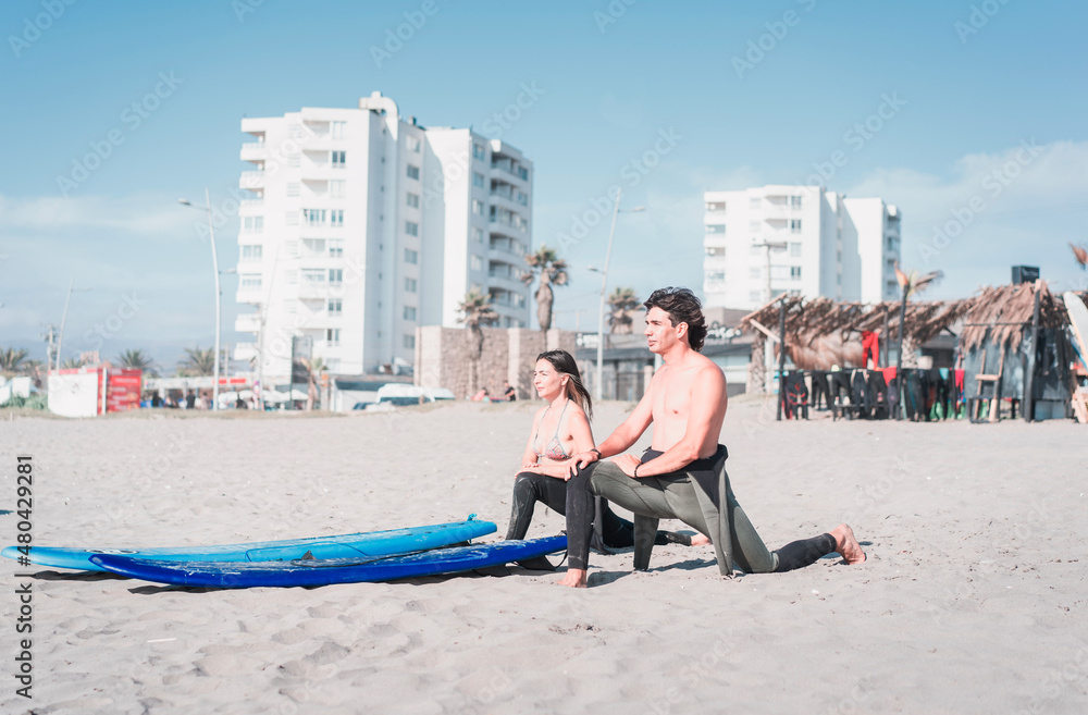 two latin surfers stretching before getting into the water to surf the waves in La Serena