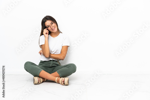 Teenager girl sitting on the floor with glasses and happy
