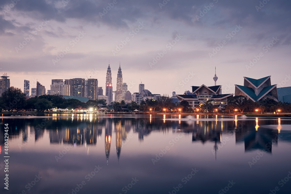 Urban skyline of Kuala Lumpur at dawn. Reflection of skyscrapers in the water surface.