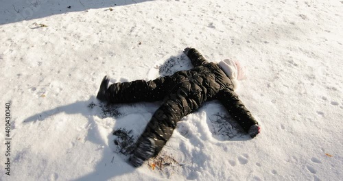 happy girl lies in the snow and makes an angel. Happy little girl