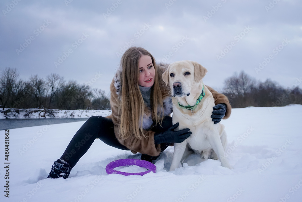 Girl with a white dog in the snow in winter