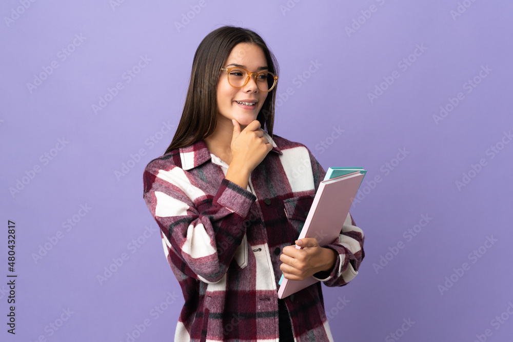Young student woman isolated on purple background looking to the side and smiling