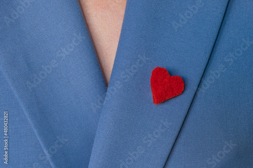 Fotografi Beautiful brooch in the form of a red heart made of felt on the lapel of a bright blue jacket