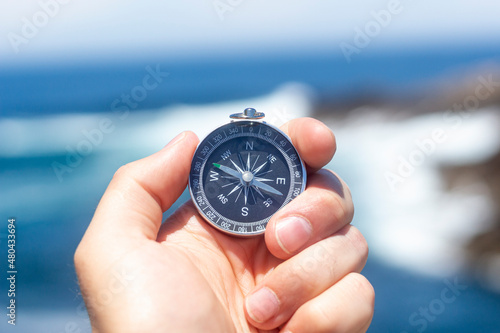 Hand holding compass for searching direction outdoor, travel, lifestyle, vacation concept.