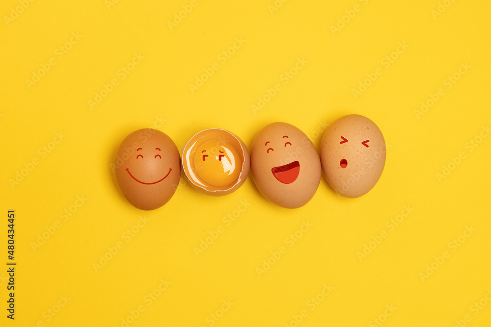 Brown chicken eggs with smile face and one broken egg with yolk on yellow background Brown chicken eggs with smile face and one broken egg with yolk on yellow background