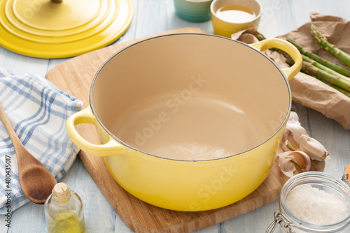 Yellow dutch oven on a wooden board with condiments around it