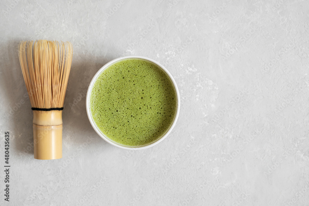 Matcha green tea and bamboo whisk on a gray background. Traditional Japanese drink. Healthy organic tea. Copy space, top view Matcha green tea and bamboo whisk on a gray background. Traditional Japanese drink. Healthy organic tea. Copy space, top view