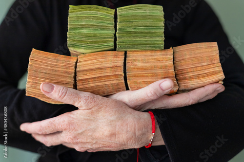 Bundles of 500 and 1000 Argentine pesos held in woman's arms photo