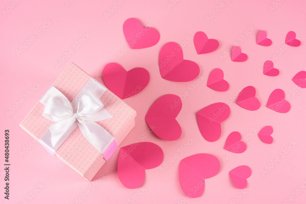 Valentine's Day celebration. Pink gift box with hearts cards on a pink background.