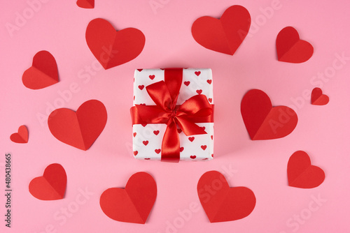 Gift for loved ones. Valentine's Day celebration. Gift box with hearts cards on a pink background.
