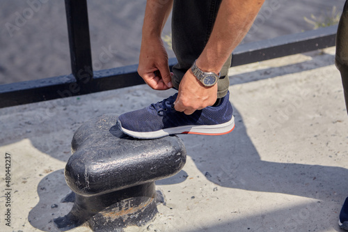 Foot is on bollard. Hands tying lace