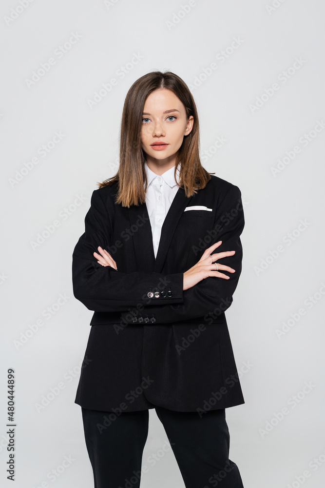 stylish woman in suit standing with crossed arms isolated on grey. stylish woman in suit standing with crossed arms isolated on grey.