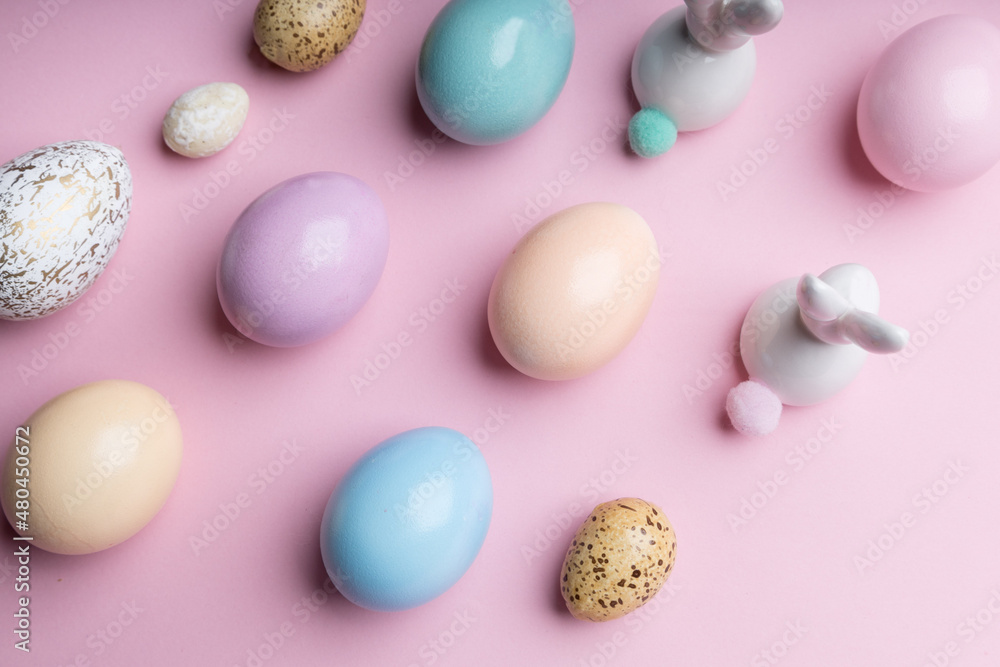Colored easter eggs with a deco bunny on a pink background. Festive spring decoration , pastel colors .