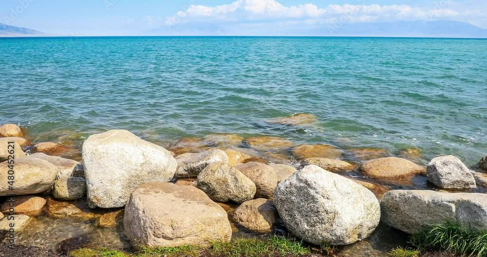 Sailimu Lake natural scenery in Xinjiang, China. Lake water lapping stone on shore. Clear lake water and rocks under blue sky. Sailimu Lake natural scenery in Xinjiang, China. Lake water lapping stone on shore. Clear lake water and rocks under blue sky.