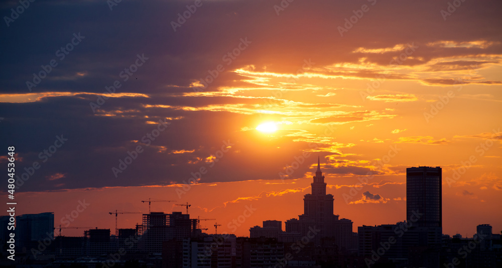 Red and orange sky with clouds and silhouette of cranes, building construction and skyscraper. Moscow.