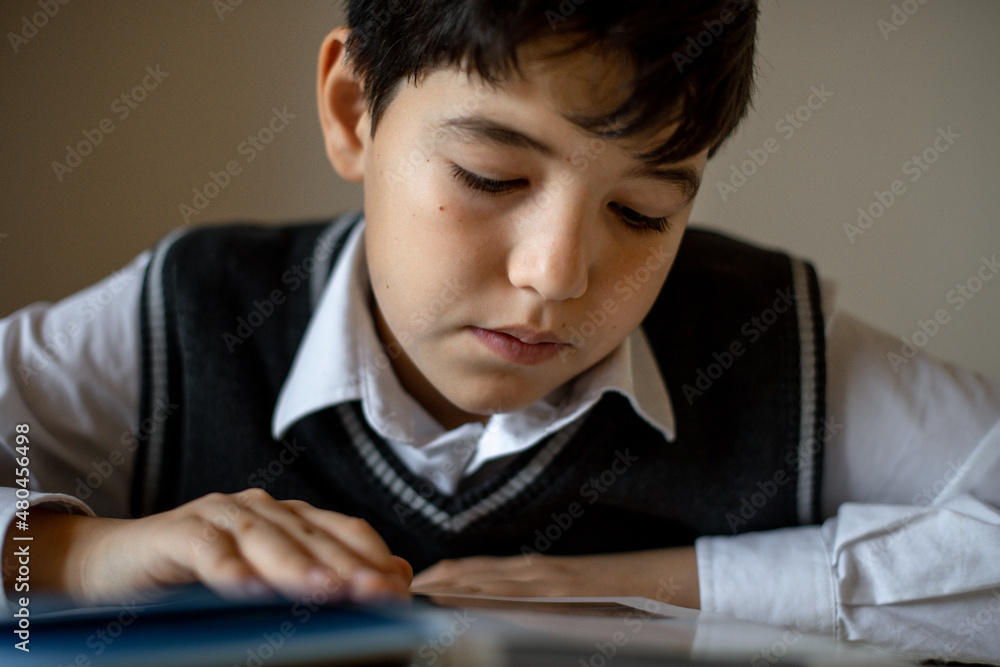 a student in a school uniform at home does homework at the table a student in a school uniform at home does homework at the table