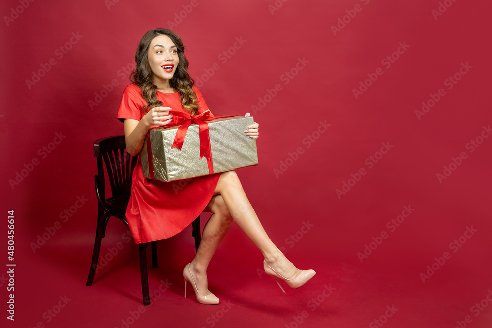 Enthusiastic woman with a gift on a red background Enthusiastic woman with a gift on a red background