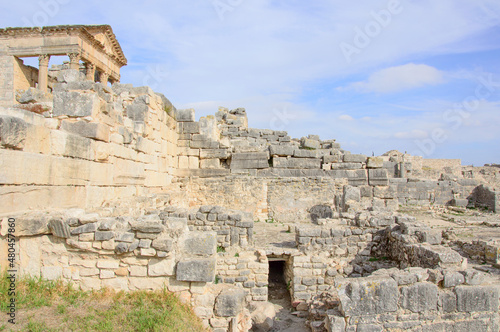 Temple of Jupiter and ancient roman ruins of Dougga in Tunisia  Africa in the sunny afternoon. Blue sky with clouds  old yellow  grey and brown stone walls and columns 