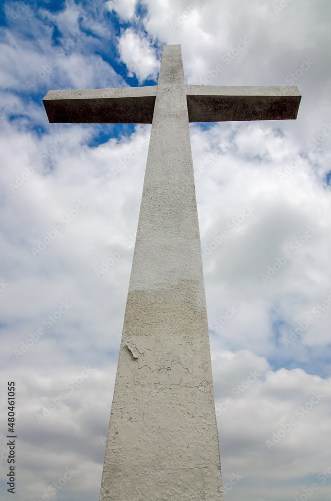 A stone cross beneath a cloudy sky.