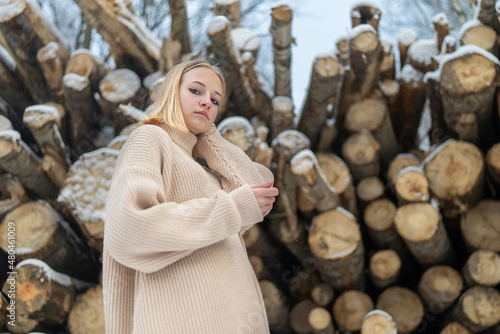 portrait girl teenager blonde on the background of a log in the snow