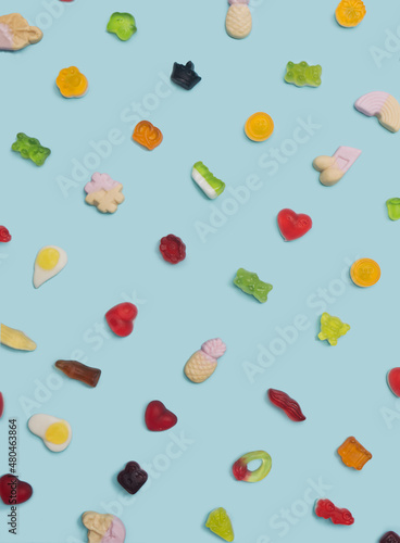 Flat lay pattern arrangement made of many different shapes and tastes soft pop gummy candies against modern blue background