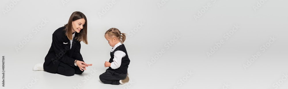 cheerful mother showing fingers to child with down syndrome on grey, banner. cheerful mother showing fingers to child with down syndrome on grey, banner.