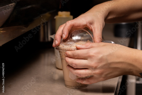 Barista making an iced coffee behind the counter of a coffee house