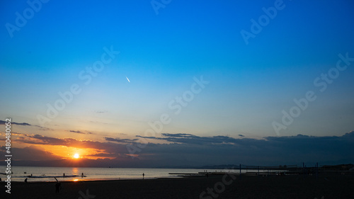 日本の綺麗な夕日と海岸の景色 サーフィンを楽しみむ人のシルエット