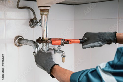 Fotobehang Technician plumber using a wrench to repair a water pipe under the sink