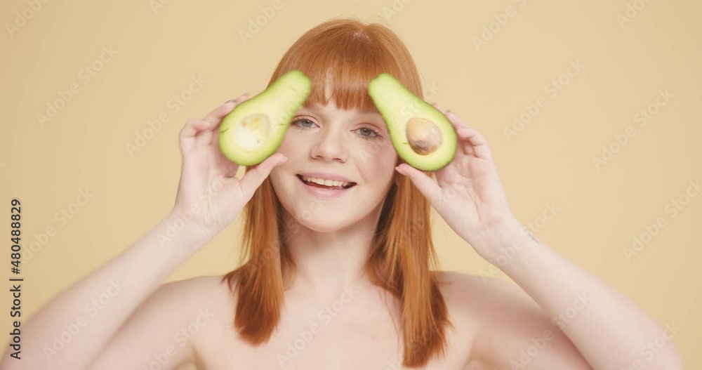 Redhead woman with bare shoulders poses with avocado Redhead woman with bare shoulders poses with avocado