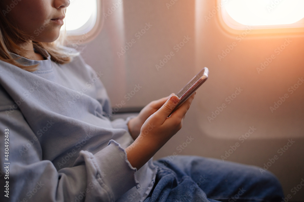 hands of a little girl plays games on smartphone in an airplane seat hands of a little girl plays games on smartphone in an airplane seat