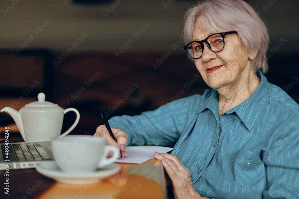 Senior woman sitting in a cafe with a cup of coffee and a laptop Freelancer works unaltered Senior woman sitting in a cafe with a cup of coffee and a laptop Freelancer works unaltered