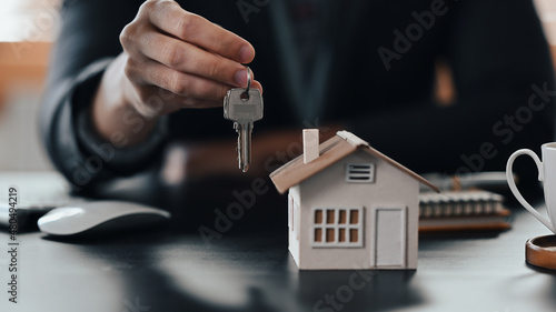 Cropped shot businessman holding house key. Insurance or loan real estate concept.