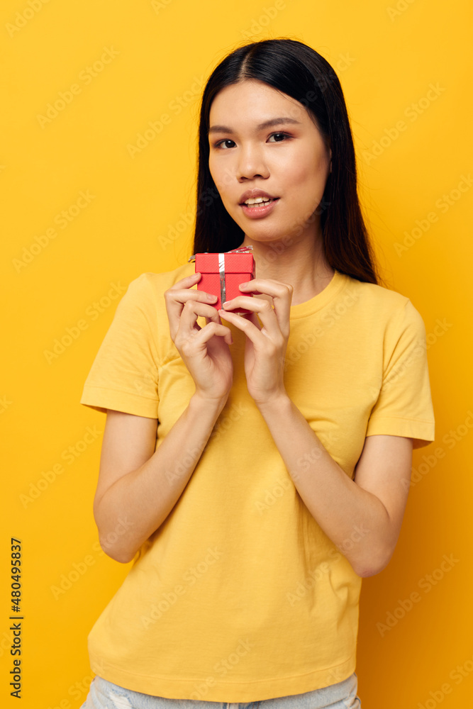 Portrait Asian beautiful young woman holding a gift box in his hands posing yellow background unaltered Portrait Asian beautiful young woman holding a gift box in his hands posing yellow background unaltered