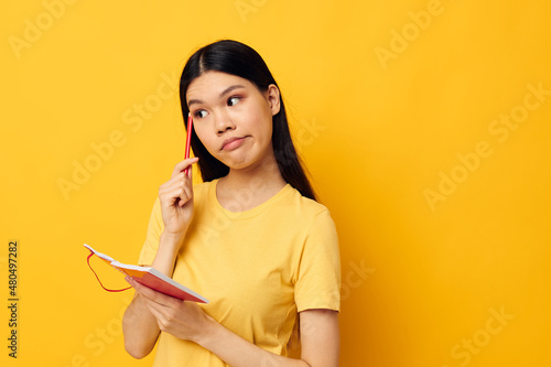 Portrait Asian beautiful young woman writes in a notebook with a pencil isolated background unaltered