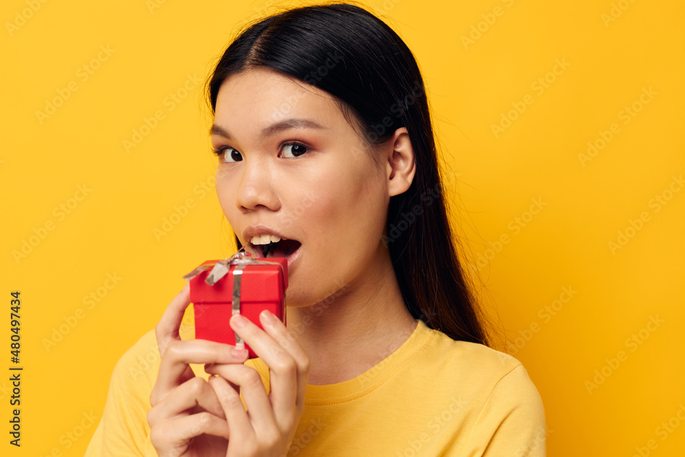 woman with Asian appearance Little red gift box fun yellow background unaltered woman with Asian appearance Little red gift box fun yellow background unaltered