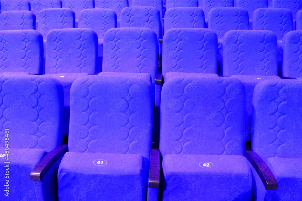 Obraz premium blue armchairs. Empty concert hall, theater chairs background ... color photo, empty cinema or concert hall. The red chairs in the cinema hall are illuminated by a light beam. Selective focus
