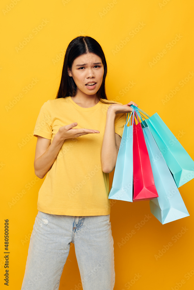 woman in a yellow T-shirt with multicolored shopping bags isolated background unaltered woman in a yellow T-shirt with multicolored shopping bags isolated background unaltered