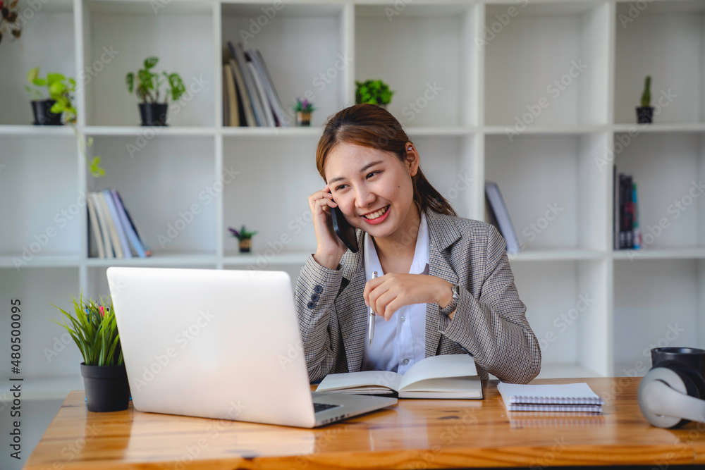 business woman at work talking on phone and taking notes, sitting at her working place in office, copy space