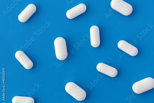 Texture of white oblong tablets lying on a blue background.
