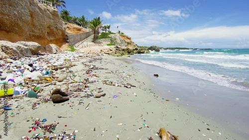 Turquoise sea waves on a sandy beach with plastic trash. Plastic waste on the rocky coast of the Dominican Republic. Pollution of the environment threatens the death and extinction of flora and fauna.