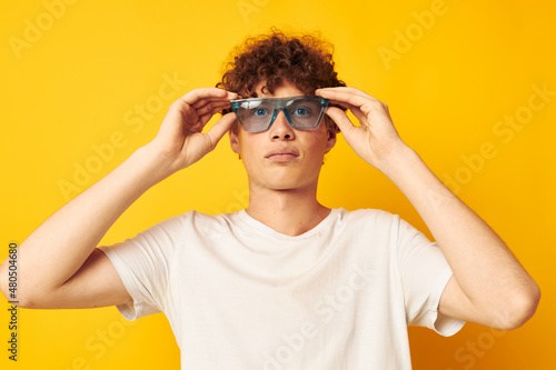 portrait of a young curly man in a white t-shirt blue fashion glasses isolated background unaltered