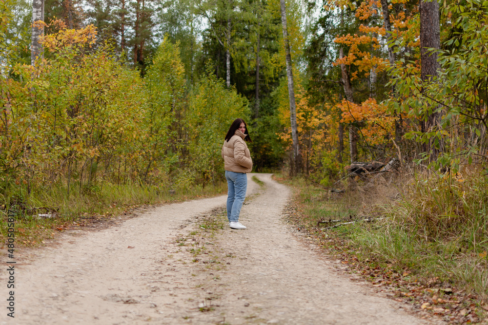 Fototapeta premium cheerful young woman in a gray jacket on the background of an autumn landscape